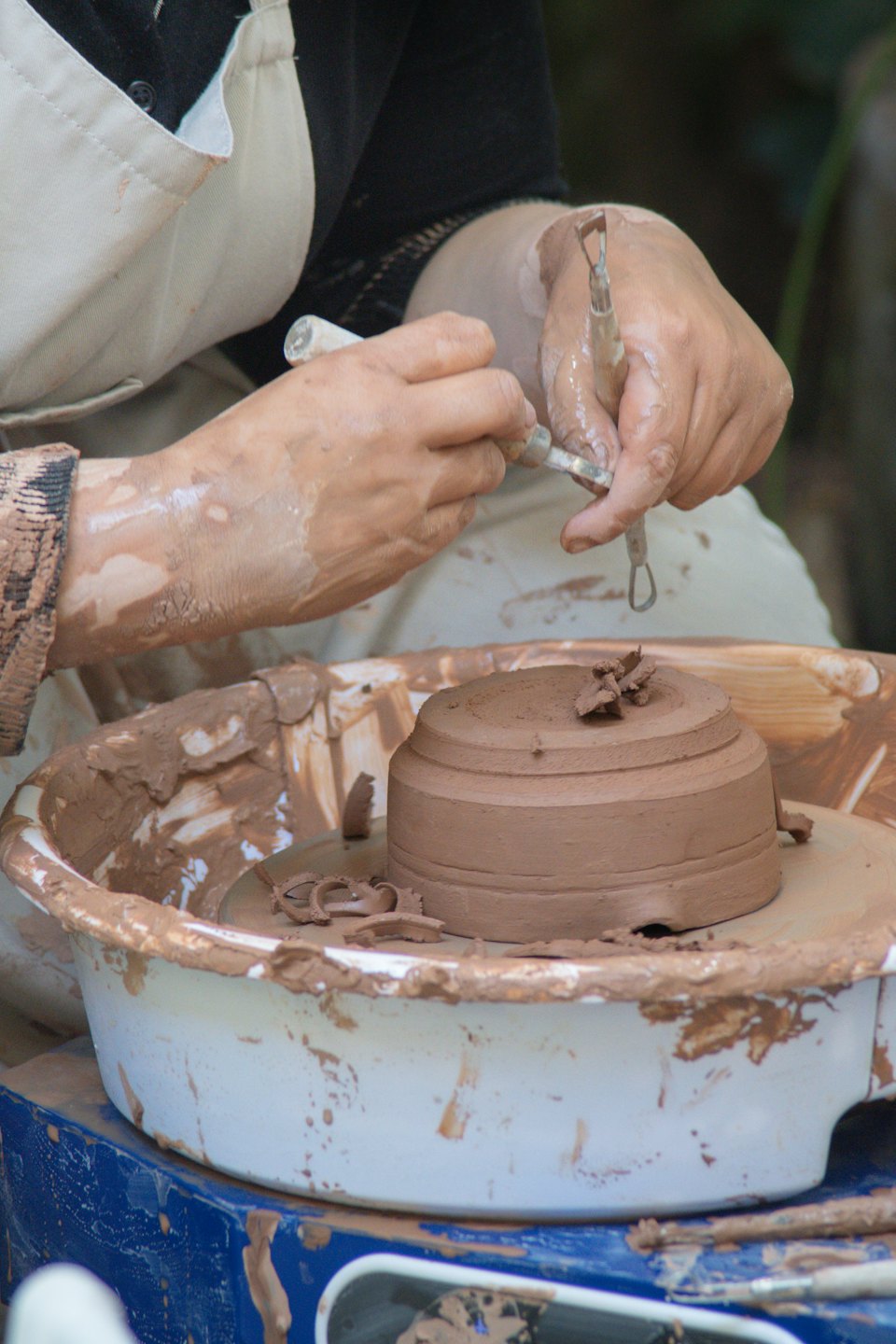 Hands shaping wet clay on a pottery wheel.