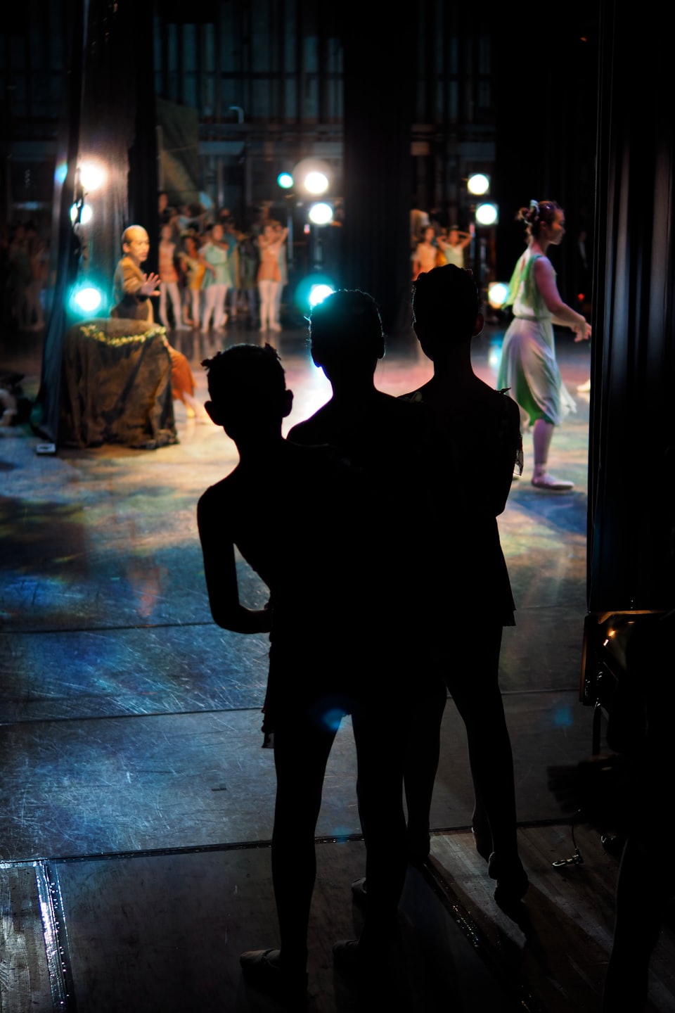 Performers in colorful costumes dance on a brightly lit stage.