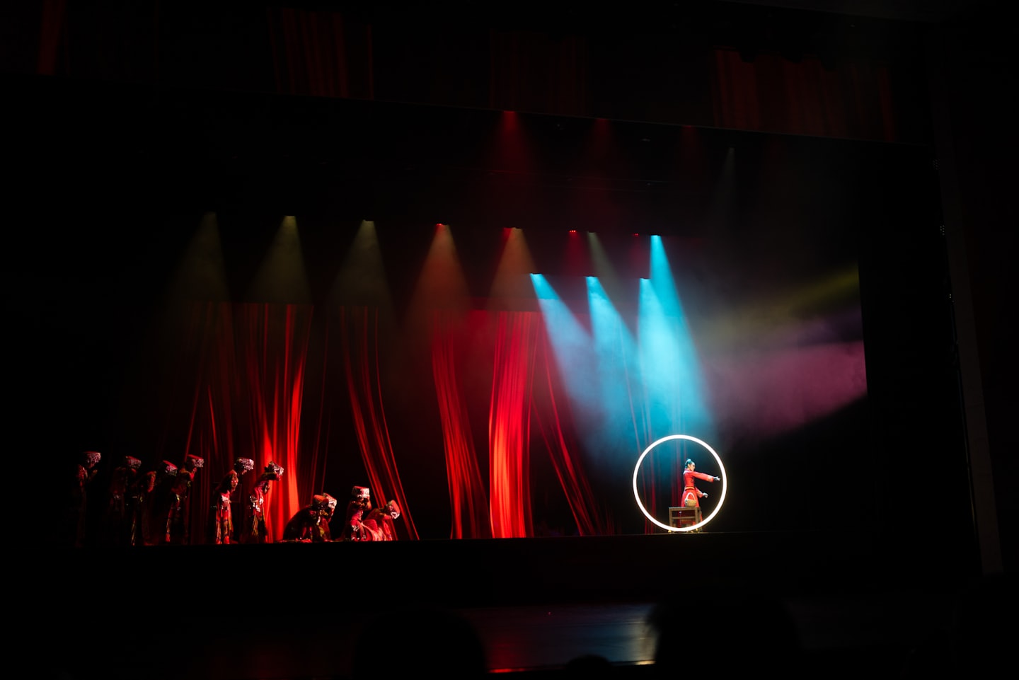 Performers in traditional costumes on a dimly lit stage.